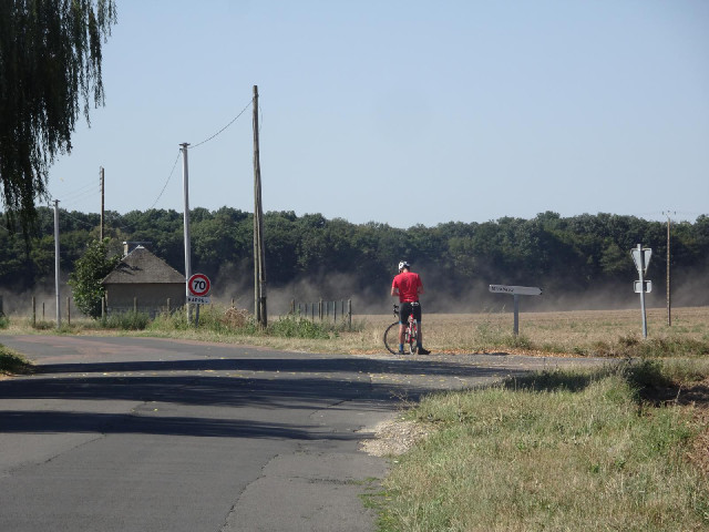 Another cyclist and some dust being kicked up by a tractor.