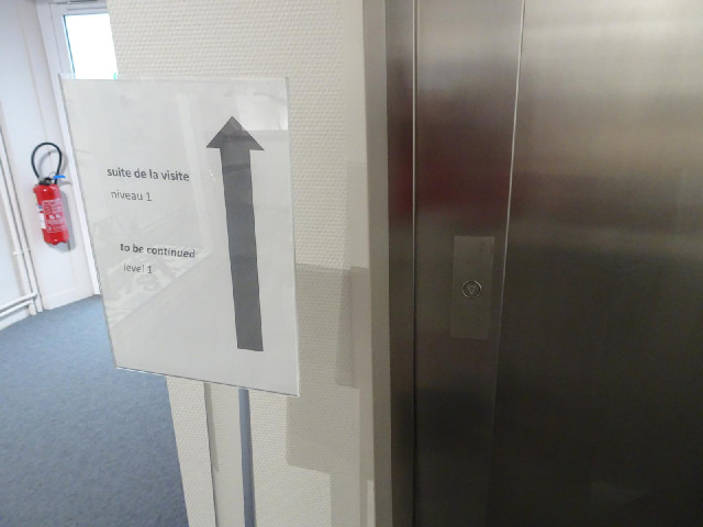 The sign says that the tour continues upstairs but there are no stairs and the lift only has a down ...