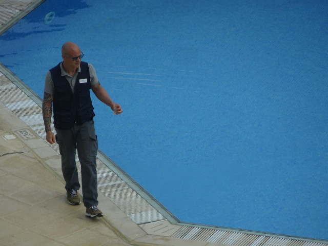 One of the hotel staff with something which he has just fished out of the pool.